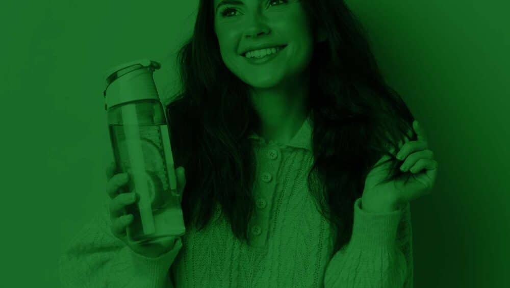 A female student holding a water bottle with PCG Everyday supergreens in the pursuit of better student health